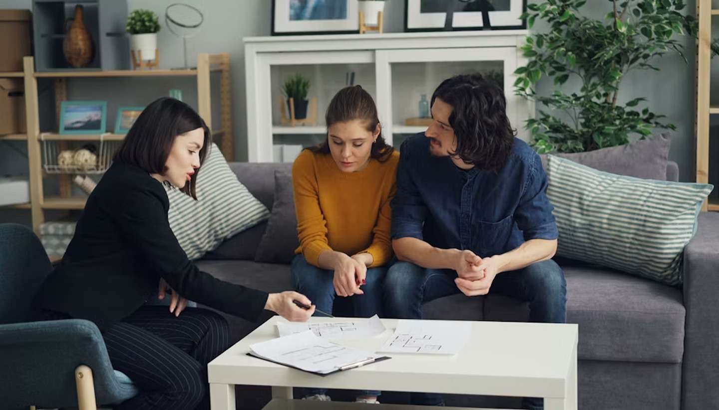 Real estate agent Palm Beach reviewing paperwork with home buyers on a couch.